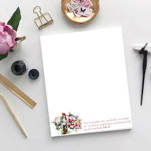 Puede incluir: Un bloc de notas blanco con una ilustración floral de un buzón con una cita de la Biblia: "Vosotros mismos sois nuestra carta, escrita en nuestros corazones, conocida y leída por todos los hombres 2 Cor. 32".