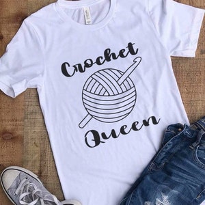 May include: White t-shirt with black text that reads "crochet queen" and a graphic of a ball of yarn and a crochet hook.
