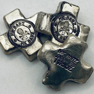May include: Three silver cross-shaped bars. Each bar has a circular emblem with a skull and crossbones and the text "MK BARZ". The bars are stamped with "MK BARZ 999+ FS 1 TROY OZ".