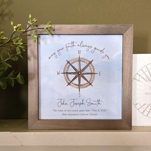 May include: A framed print with a compass design and the text "May your faith always guide you". The print also includes the name "John Joseph Smith" and the date "May 4, 2025".