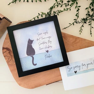 May include: A black framed print featuring a cat illustration and the text "Some angels don't have wings. Sometimes they have whiskers. Pookie." A card with the text "So sorry for your loss" is also present.