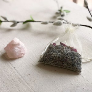 May include: A small pink rose quartz crystal and a white organza bag filled with dried lavender and rose petals.