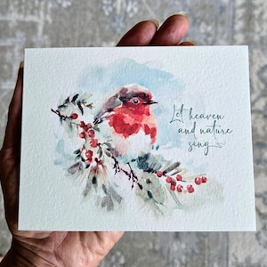 May include: Watercolor greeting card featuring a red-breasted robin perched on a branch with red berries. The card has the text "Let heaven and nature sing" in cursive script. The background is a soft blue and white.