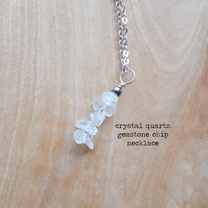 K&ouml;nnte beinhalten: Halskette mit silberner Kette und Anh&auml;nger aus klaren Kristallquarz-Edelstein-Chips. Eine kleine, dunkle Perle befindet sich in der N&auml;he der Oberseite des Anh&auml;ngers. Der Text im Bild lautet "crystal quartz gemstone chip necklace."