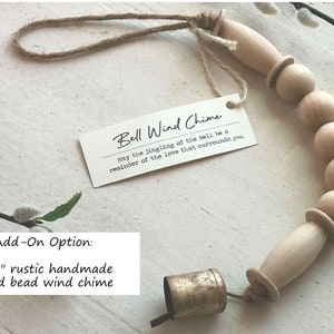 May include: A 12-inch rustic handmade wood bead wind chime with a gold bell. The chime is made of natural wood beads and has a simple, elegant design. "May the jingling of the bell be a reminder of the love that surrounds you."