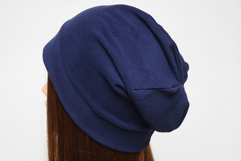May include: A navy blue slouchy beanie hat made of soft fleece fabric.