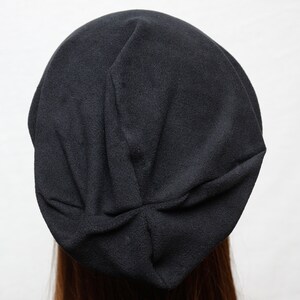May include: A black beanie hat made of soft fabric. The hat is folded and has a slouchy fit.