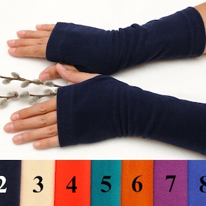 May include: A pair of navy blue fingerless arm warmers made of fleece. The arm warmers are shown on a person's arms. The image also shows nine color swatches of the arm warmers.