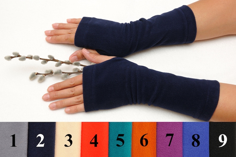 May include: A pair of navy blue fingerless arm warmers made of fleece. The arm warmers are shown on a person's arms. The image also shows nine color swatches of the arm warmers.