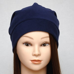May include: A navy blue beanie made of soft fabric. The beanie is folded down at the top and has a simple design.