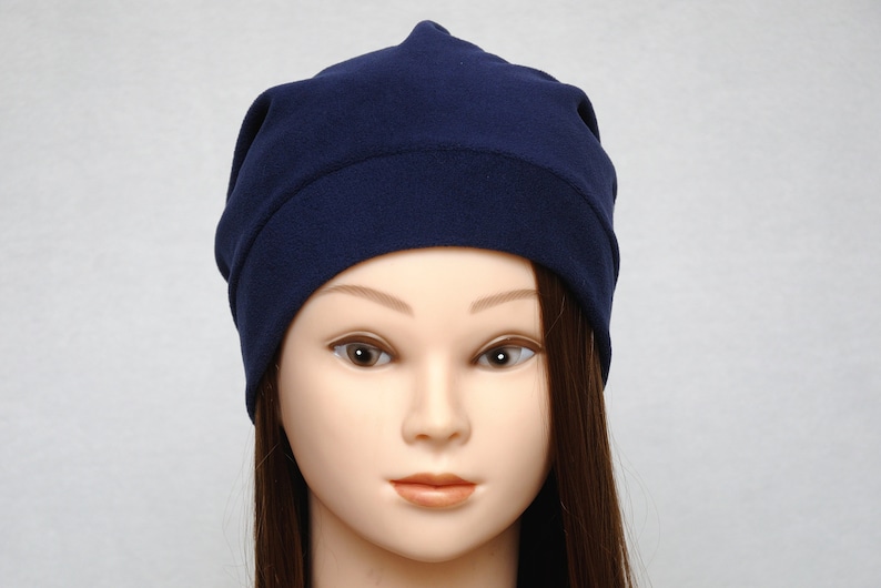 May include: A navy blue beanie made of soft fabric. The beanie is folded down at the top and has a simple design.