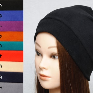 May include: A black slouchy beanie hat made of soft fabric. The hat is folded over at the top and has a simple design.