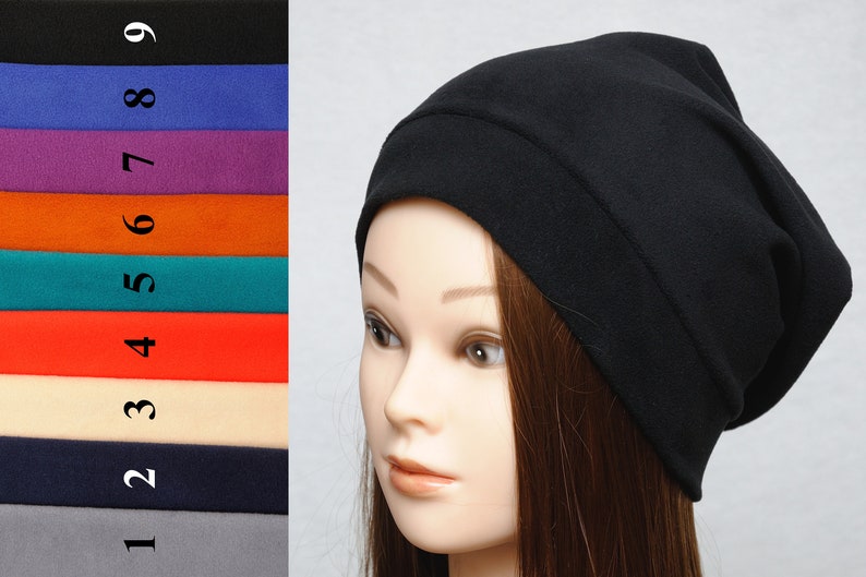 May include: A black slouchy beanie hat made of soft fabric. The hat is folded over at the top and has a simple design.
