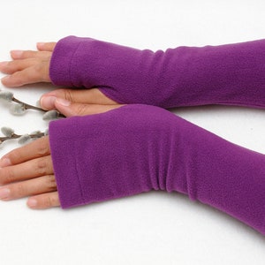 May include: A pair of purple fleece fingerless gloves. The gloves are long and extend past the wrist.