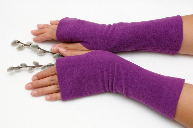 May include: A pair of purple fleece fingerless gloves. The gloves are long and extend past the wrist.