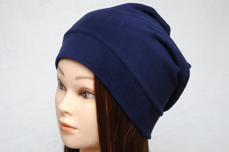 May include: A navy blue fleece beanie hat. The hat is folded down at the top, creating a slouchy look.
