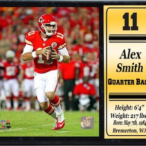 May include: A black and gold framed plaque with a photo of a football player wearing a red jersey and white pants. The plaque includes the player's name, number, position, and biographical information. The text on the plaque reads: "11 Alex Smith QUARTER BACK Height: 6'4" Weight: 217 lbs Born: May 7th, 1984 Bremerton, WA"