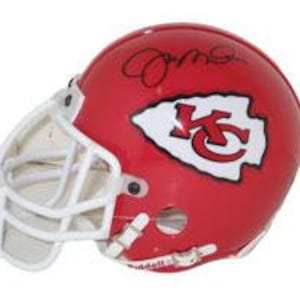 Könnte beinhalten: Ein roter American-Football-Helm mit weißem Gesichtsschutz. Der Helm zeigt ein weißes und rotes Logo mit den Buchstaben "KC" innerhalb einer weißen Umrandung von Missouri. Oben ist eine Unterschrift mit schwarzer Tinte zu sehen.