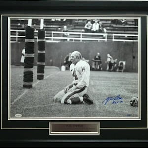 以下が含まれることがあります： フィールドにひざまずいているアメリカンフットボール選手の白黒写真。選手は背番号14のジャージを着ています。写真は選手によって「Y.A. Tittle」とサインされています。