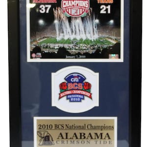 Könnte beinhalten: Ein gerahmtes Foto des BCS National Championship Spiels von 2010, das die Alabama Crimson Tide zeigt, die die Texas Longhorns mit 37-21 besiegten. Das Foto ist von einem schwarzen Rahmen und einer blauen Passepartout umgeben. Das Foto enthält den Text "2008 National Champions", "Alabama", "37", "Texas", "21", "January 7, 2010", "citi BCS National Championship Pasadena 2010", "2010 BCS National Champions", "Alabama Crimson Tide".