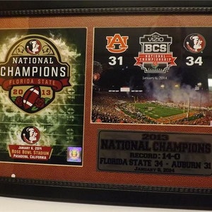 Könnte beinhalten: Ein gerahmtes Foto, das an den Sieg der Florida State Seminoles bei der National Championship 2013 gegen die Auburn Tigers erinnert. Das Foto zeigt das Ergebnis, 34-31, und das Datum, 6. Januar 2014.