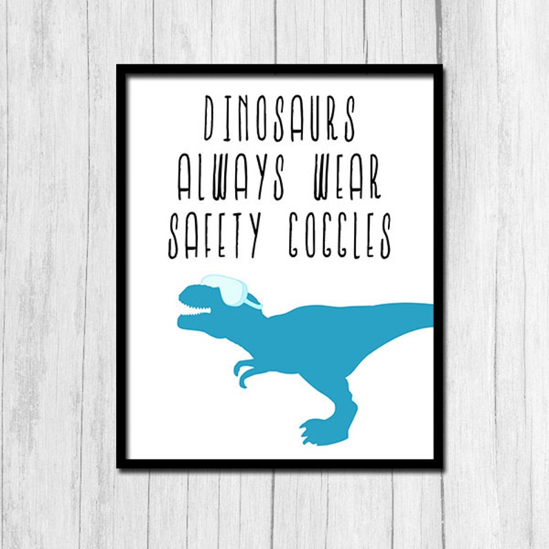 May include: A white framed print with a blue dinosaur wearing safety goggles. The text reads "Dinosaurs Always Wear Safety Goggles".