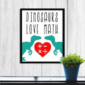 May include: A white framed print with the text "Dinosaurs Love Math" in black. Two green dinosaur silhouettes face each other with a red heart in between. The heart has math symbols inside: plus, minus, multiply, and divide.
