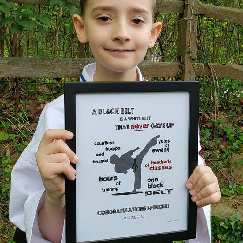K&ouml;nnte beinhalten: Ein schwarz-wei&szlig;es Motivationsposter mit einer Silhouette einer Person in einer Karate-Pose. Der Text lautet "Ein schwarzer G&uuml;rtel ist ein wei&szlig;er G&uuml;rtel, der niemals aufgegeben hat." Es listet auch die Leistungen eines schwarzen G&uuml;rtels auf, darunter unz&auml;hlige Beulen und blaue Flecken, Jahre des Schwei&szlig;es, Hunderte von Kursen und Stunden des Trainings. Das Poster ist signiert und datiert mit "23. Mai 2020" und sagt "Herzlichen Gl&uuml;ckwunsch Spencer!"