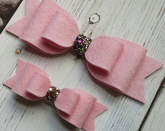Può includere: Due fiocchi di feltro rosa con centri scintillanti. Il fiocco più grande è largo circa 10 cm e il più piccolo circa 5 cm.