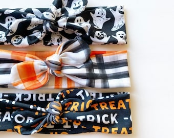 Może przedstawiać: Trzy czarne i białe opaski na głowę z pomarańczowo-białą kratą i czarno-białym napisem "trick or treat".