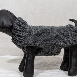 Puede incluir: Jersey de punto gris para perro en un maniqu&iacute; negro. El jersey es de dise&ntilde;o sencillo con cuello alto.