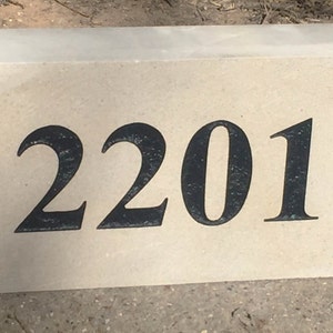 May include: A beige concrete house number plaque with the number 2201 printed in black.