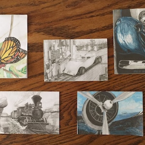 Puede incluir: Cinco tarjetas diferentes con varios dibujos. La primera tarjeta tiene una mariposa en una hoja verde. La segunda tarjeta tiene un dibujo en blanco y negro de un coche en un garaje. La tercera tarjeta tiene un pájaro azul sobre un fondo blanco y negro. La cuarta tarjeta tiene un dibujo en blanco y negro de un tren. La quinta tarjeta tiene un dibujo azul y blanco de una hélice.