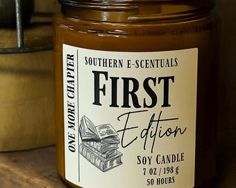 May include: A brown glass jar soy candle with a white label featuring the text Southern E-Scentuals, First Edition, One More Chapter, 7 oz / 198 g, 50 hours, and a black and white line drawing of a stack of three open and closed books.