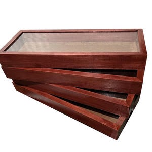 Op de afbeelding: Een stapel van vier roodbruine houten displaydozen. Elke doos heeft een doorzichtig glazen bovenkant en een lichtgekleurd interieur. De dozen zijn in een verspringende, open configuratie gerangschikt.