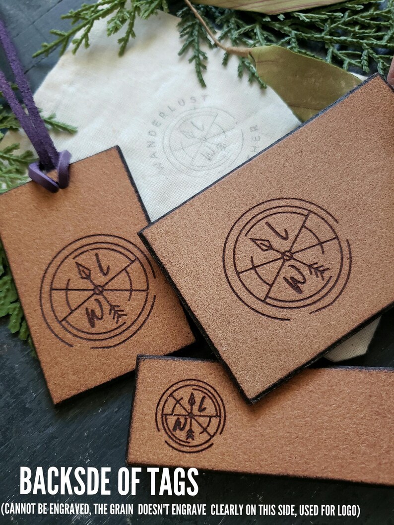 May include: Close-up of three brown leather tags with a compass design engraved on each. The text "BACKSDE OF TAGS" and "(CANNOT BE ENGRAVED, THE GRAIN DOESN'T ENGRAVE CLEARLY ON THIS SIDE, USED FOR LOGO)" is printed on the bottom of the image.
