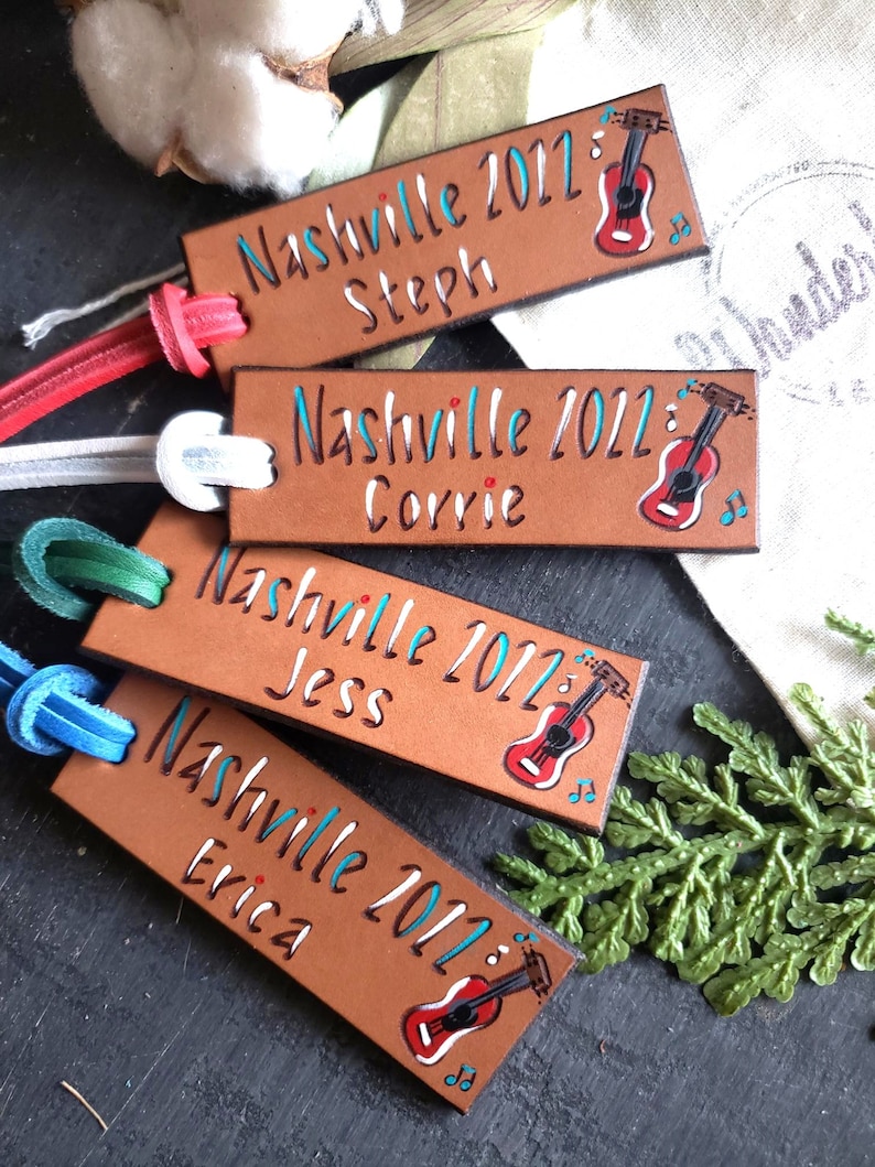 May include: Four brown leather keychains with a guitar design and the text "Nashville 2012" with a different name on each keychain: Steph, Corrie, Jess, and Erica.