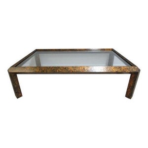 May include: A rectangular glass-top coffee table with a gold-toned metal frame. The frame has a textured, marbled finish.