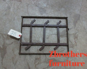 May include: A rusty metal grate with a rectangular shape and a simple design. The grate has four horizontal bars and three vertical bars, creating a grid pattern. The grate is sitting on a light gray tiled floor.