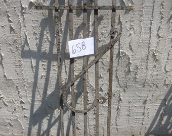 May include: A rusty metal gate with decorative scrollwork and a white tag with the number 658 written on it.