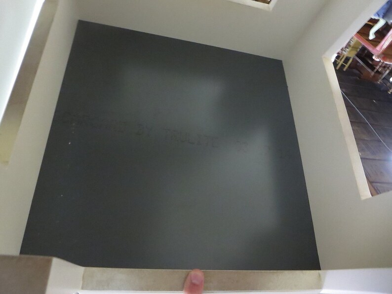 May include: A dark gray floor with a white trim around the edges. The floor is in a room with white walls and a white ceiling.