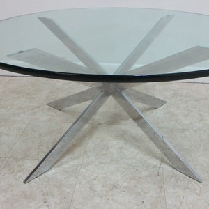 May include: A round glass top coffee table with a chrome starburst base.