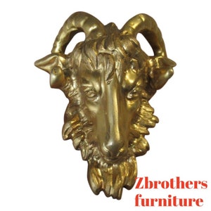May include: A gold-colored metal ram's head sculpture with detailed features, including horns, fur, and a realistic face. The sculpture is a decorative piece for home decor.