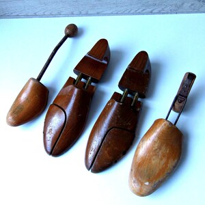 K&ouml;nnte beinhalten: Vier Schuhspanner aus Holz in verschiedenen Braunt&ouml;nen. Zwei sind dunkler, die anderen heller. Einer hat eine Metallfeder und einen Holzknauf. Die Schuhspanner dienen dazu, die Form der Schuhe zu erhalten.