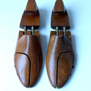 K&ouml;nnte beinhalten: Zwei Schuhspanner aus Holz, die dazu dienen, die Form von Schuhen zu erhalten. Die Schuhspanner sind aus dunkelbraunem Holz gefertigt und haben ein geteiltes Zehendesign mit Messingbeschl&auml;gen. Wahrscheinlich Vintage.