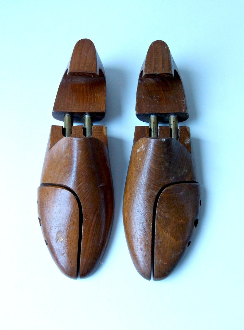 K&ouml;nnte beinhalten: Zwei Schuhspanner aus Holz, die dazu dienen, die Form von Schuhen zu erhalten. Die Schuhspanner sind aus dunkelbraunem Holz gefertigt und haben ein geteiltes Zehendesign mit Messingbeschl&auml;gen. Wahrscheinlich Vintage.