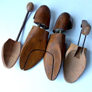 K&ouml;nnte beinhalten: Vier Schuhspanner aus Holz in verschiedenen Designs. Sie bestehen aus dunkelbraunem Holz und verf&uuml;gen &uuml;ber Metall- und Federmechanismen. Ein Spanner hat einen langen Griff mit einem Holzkopf. Auf wei&szlig;em Hintergrund.