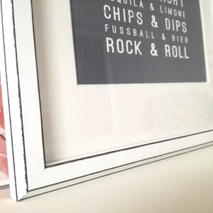 Puede incluir: Marco de imagen blanco con una impresi&oacute;n en blanco y negro en el interior. La impresi&oacute;n dice "Tequila & Limone, Chips & Dips, Fussball & Bier, Rock & Roll".