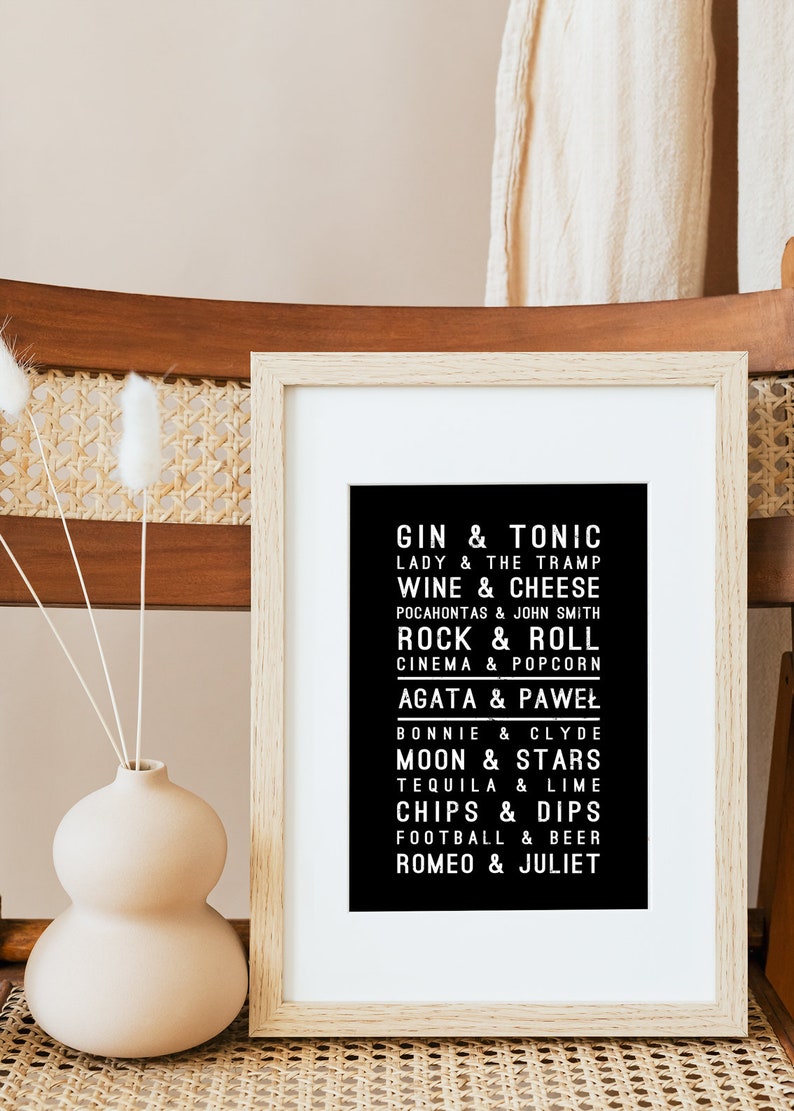 K&ouml;nnte beinhalten: Ein schwarz-wei&szlig;er gerahmter Druck mit einer Liste von Phrasen in einer Vintage-Schriftart. Die Phrasen beinhalten "Gin & Tonic", "Lady & The Tramp", "Wine & Cheese", "Rock & Roll", "Agata & Paweł", "Moon & Stars", "Chips & Dips", "Football & Beer" und "Romeo & Juliet".