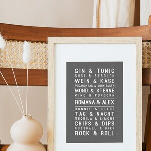 May include: A framed print with a black background and white text. The text lists various pairs of words in German, such as "Gin & Tonic", "Susi & Strolch", and "Wein & K&auml;se".